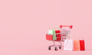 Alışveriş konsepti: karton veya karton kutular ve pembe arka planda kırmızı alışveriş arabasında alışveriş torbası. Çevrimiçi alışveriş tüketicileri evden ve teslimat servisinden alışveriş yapabilirler. kopyalama alanı ile