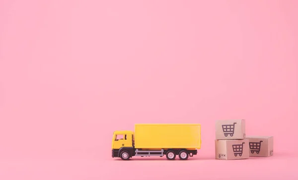 Logistics, and delivery service - Cargo truck and paper cartons or parcel with a shopping cart logo on Pink background. Shopping service on The online web and offers home delivery. with copy space
