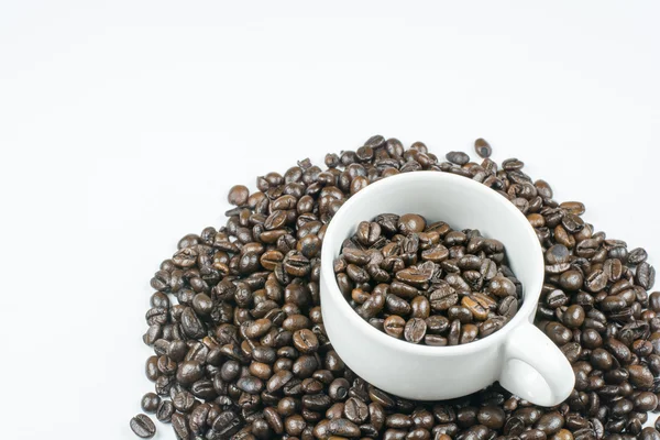 Granos de café en taza de café aislado en blanco — Foto de Stock