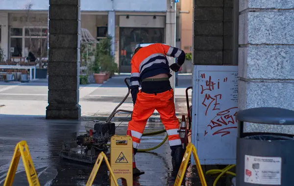 İtalyan İşçi Lecco, Lombardy, İtalya 'da halka açık bir alanı yıkıyor.