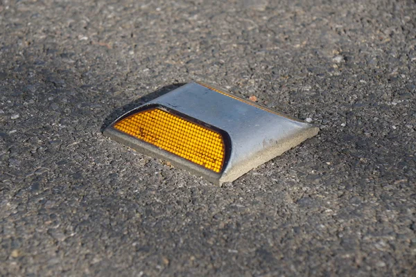 Metalen weg stud met gele reflector op asfaltweg Stockfoto
