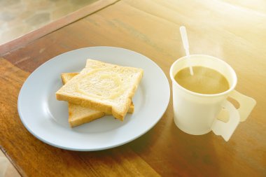 Ahşap masa günü kahvaltıda tatlı süt ile tepesinde sıcak kahve ve ekmek tost