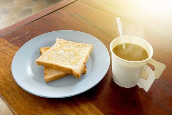 Café quente e pão tostado coberto com leite doce para o café da manhã na mesa de madeira — Fotografia de Stock