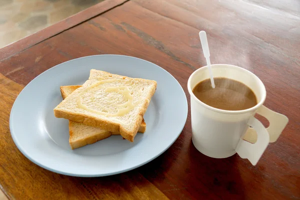 Café caliente y pan tostado cubierto con leche dulce para el desayuno en la mesa de madera — Foto de Stock