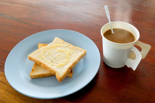 Café caliente y pan tostado cubierto con leche dulce para el desayuno en la mesa de madera — Foto de Stock