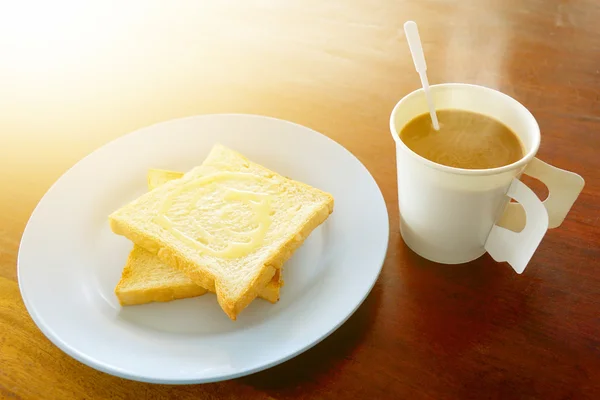 Café caliente y pan tostado cubierto con leche dulce para el desayuno y el sol de la mañana tocado — Foto de Stock