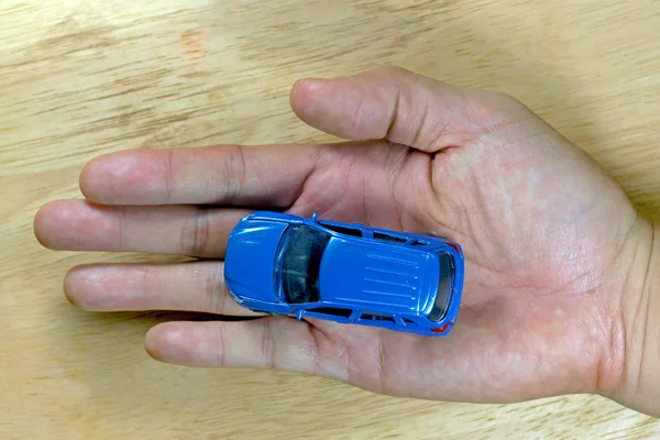 Niebieski Samochodzik w męskiej ręki powyżej drewniany stół dla podróży koncepcja. — Zdjęcie stockowe