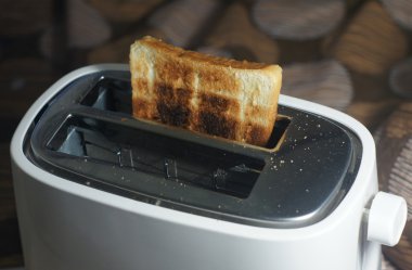 Kirli beyaz ekmek kızartma makinesi ve yanmış tost (seçici odak, koyu tonu)