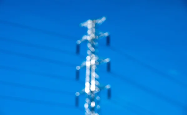 Rozmazaný vysokého napětí post nebo energie přenosové linky věž a modrá obloha — Stock fotografie