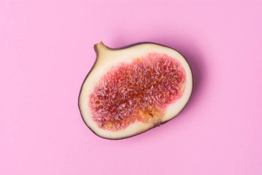 Pembe arka planda incirin yarısı. Olgun tropik meyve.
