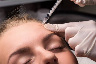 Kadın yüzüne botulinyum iğnesi yaptırıyor. Gençleştirme ve nemlendirme prosedürü