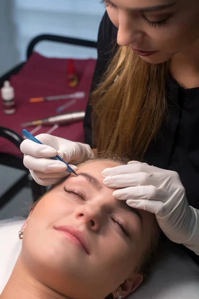 Beautician plucking eyebrows. Eyebrow care in a beauty salon.