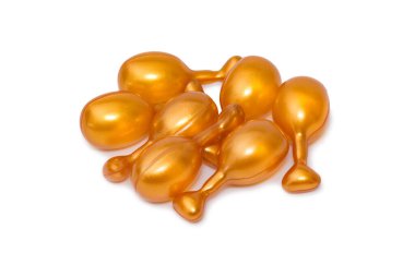 Beyaz arka planda izole edilmiş altın kapsüller. Yüz serumu