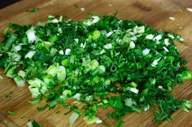 Doğranmış taze yeşil dereotu yakından görmek, mutfaktaki ahşap tahtada dereotu kesmek.