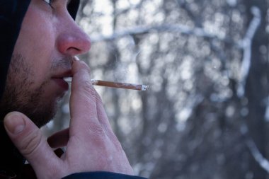 Kışın sigara içen bir adam. Erkek eli.