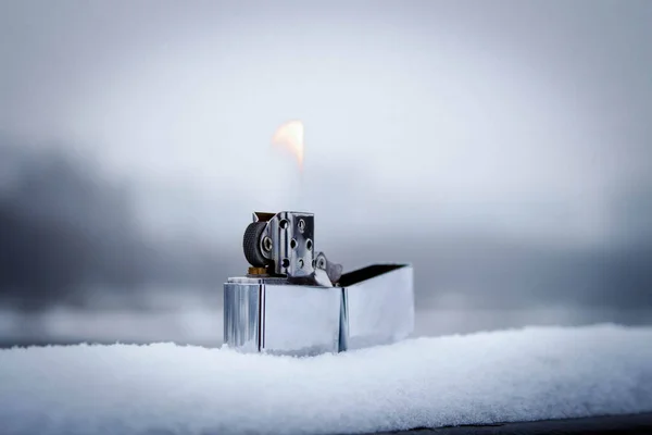 Flaming lighter zippo. Lighter on snow in the winter Stock Photo