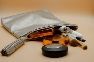 Dekoratif güzellik ürünleriyle dolu kozmetik çanta. Fırçalar, pudra, kontur paleti çantadan düştü. Makyaj 