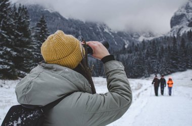 Sırt çantalı kadın dürbünle bakıyor. Kış sisli dağlarda.. 