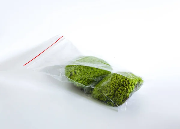 Декоративный мох в пластиковом пакете изолирован на белом фоне. зеленый цветок растений. — стоковое фото