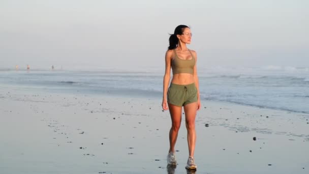 Kumsalda yürüyen sporcu kadın Bali 'de sabah güneşinde spor yapıyor. — Stok video