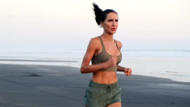 Kadın plajda koşuyor. Gün doğumunda spor yapıyor. — Stok video