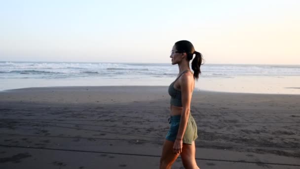 Kadın plajda yürüyor. Bali 'de. Gün doğumunda spor yapıyor. — Stok video