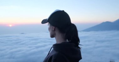 Uçurumda oturan kadın dağları ve bulutları rahatlatıyor Bali Agung