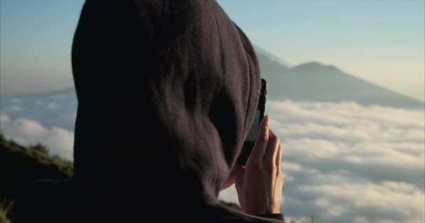 Mooie reizende vrouw staat op de top van de berg bij zonsondergang en met behulp van telefoon — Stockvideo