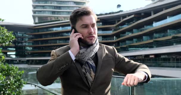 Mladý muž v zimním oblečení s chytrým telefonem v ruce, na ulici — Stock video