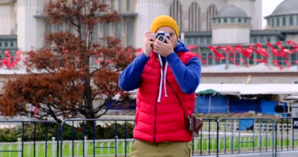 A man takes a photo, looking at the camera, against the background of a mosque — Stock Video