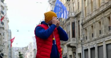 Kırmızı yelekli bir turist Salzburg 'da dolaşıyor ve kamerayla fotoğraf çekiyor.