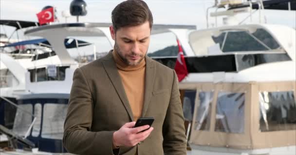 Glücklich lächelnder Geschäftsmann im braunen Anzug und mit modernem Smartphone, Bebek — Stockvideo