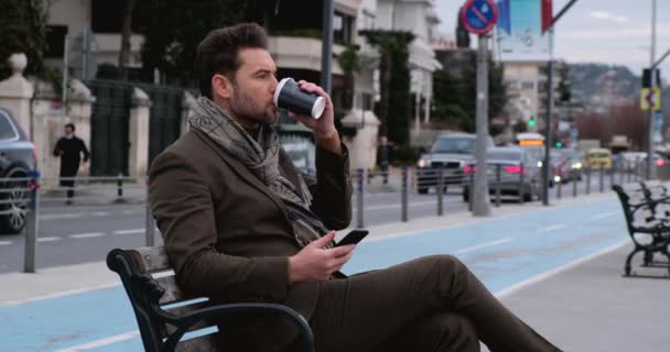 Homem usando telefone inteligente.Empresário no banco de estacionamento com café usando telefone móvel — Vídeo de Stock