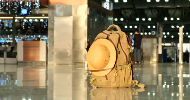 Ein Touristenrucksack mit einem Entdeckerhut auf dem Flughafenboden — Stockvideo