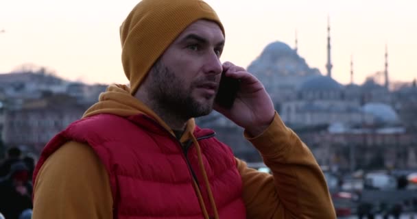 Hombre cerca de la mezquita, en el parque, hablando por teléfono móvil — Vídeos de Stock