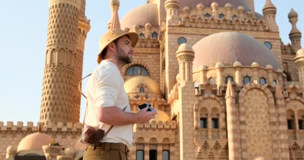 Um turista fica com uma câmera perto da mesquita — Vídeo de Stock