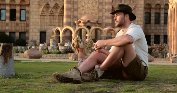 Hombre guapo en estilo vaquero se sienta en la hierba, con el phone.mosque — Vídeo de stock