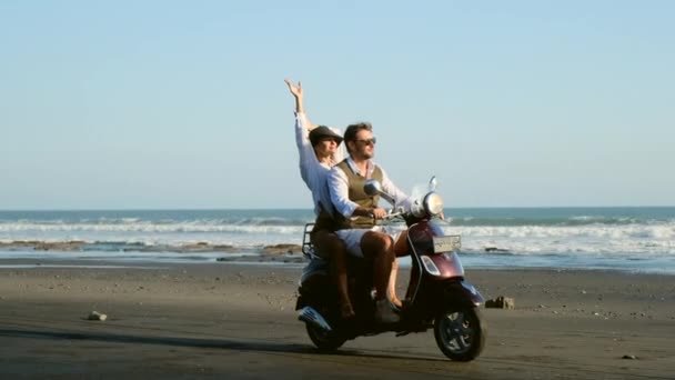 Os viajantes descansam na praia em uma scooter retro, passeio na areia perto do oceano — Vídeo de Stock