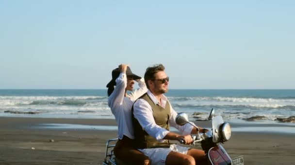 Красива молода пара в сонцезахисних окулярах посміхається під час їзди на скутері — стокове відео