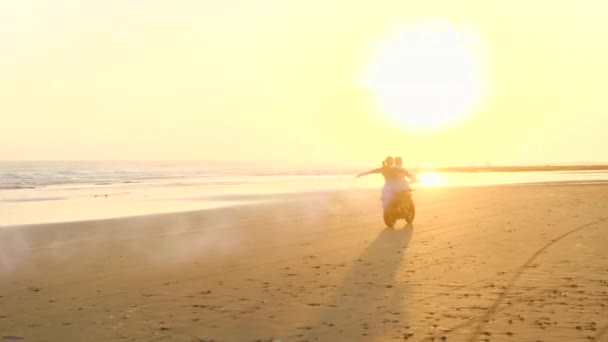 Hermosa pareja en un ciclomotor retro disfrutar de la vida en la playa con bombas de colores — Vídeo de stock