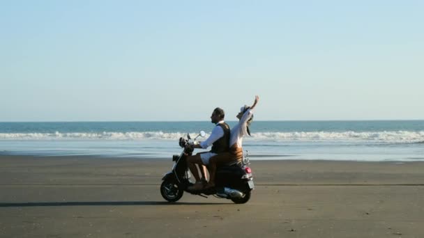 Hermosa pareja europea en un ciclomotor retro disfrutar de la vida en la playa del canario — Vídeo de stock