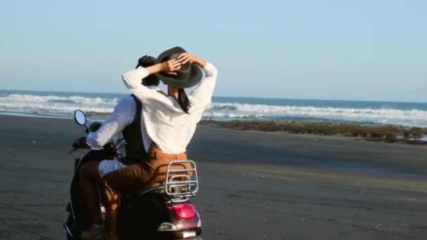 Gelukkig vrolijk paar in liefde op aangepaste motorfiets rijden op het strand in de buurt van Ocean — Stockvideo