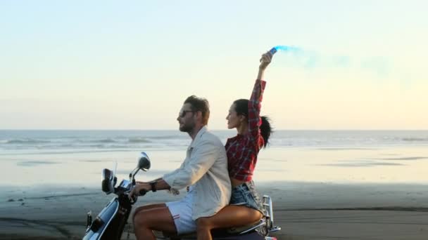 Sexy chica en pantalones cortos abrazó a un chico en motocicleta cerca del océano con humo de color — Vídeo de stock