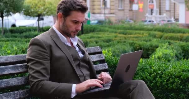 Giovane uomo d'affari in abito elegante nel quartiere degli affari con tè e computer portatile — Video Stock
