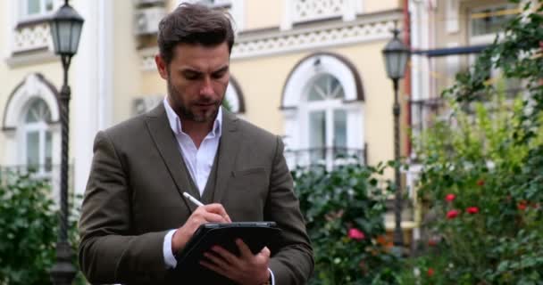 Junger liebenswerter Mann schaut auf digitales Tablet.Ein Mann im Anzug benutzt ein Tablet — Stockvideo
