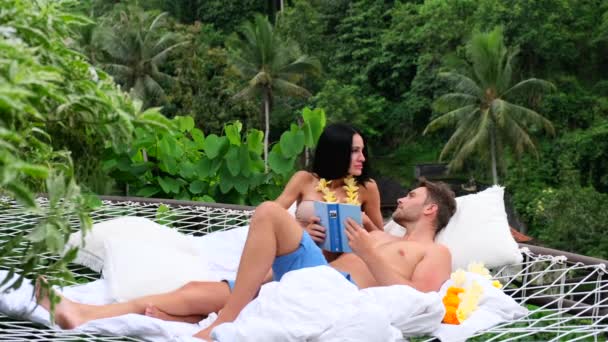 性感女人与男人一起阅读一本书热带森林，别墅，度假，度蜜月 — 图库视频影像