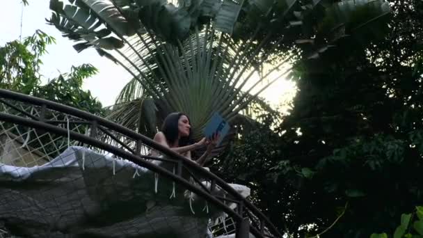 Femme se relaxant dans l'hamac sur la forêt tropicale avec livre, vaction d'été. — Video