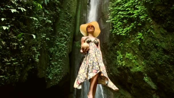 Mulher turista beber leite de coco perto de cachoeira em férias — Vídeo de Stock