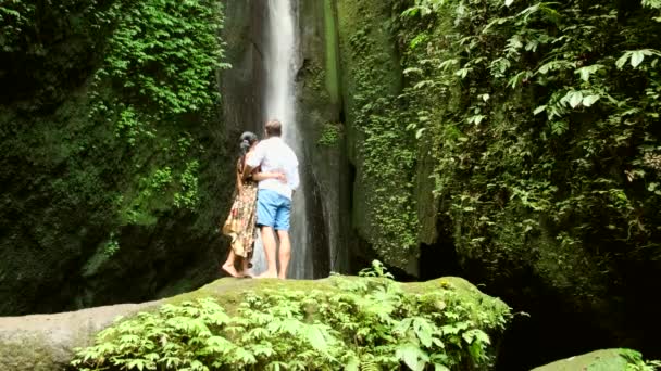Pár szerelmes közel egy vízesés a trópusokon, nászút — Stock videók