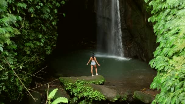 Jonge sexy vrouw met tatoo kijkend naar de waterval in jungles. Bali, Indonesië — Stockvideo